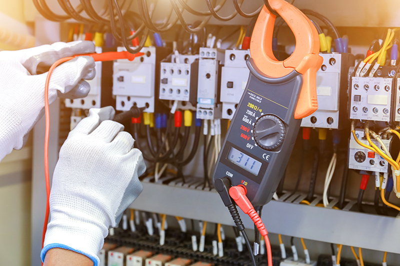 electrician measurements with multimeter tester in control panel